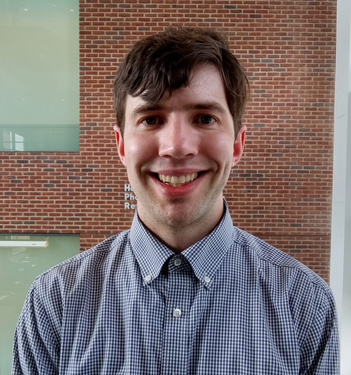 Portrait of Gregory Riley in front of brick wall